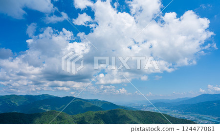 藍天上有許多白雲，山巒被綠色植物包裹著 124477081
