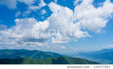 Many white clouds in the blue sky and mountains wrapped in greenery 124477083