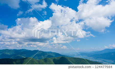 Many white clouds in the blue sky and mountains wrapped in greenery 124477084