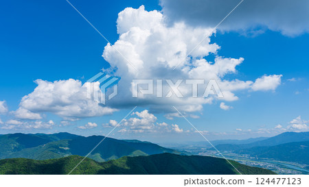 Many white clouds in the blue sky and mountains wrapped in greenery 124477123