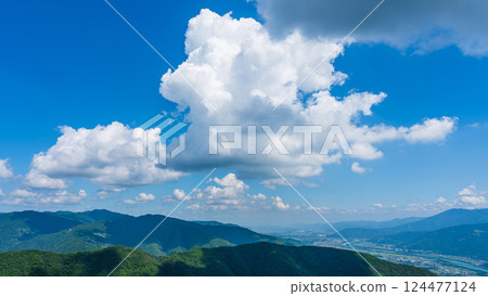 Many white clouds in the blue sky and mountains wrapped in greenery 124477124
