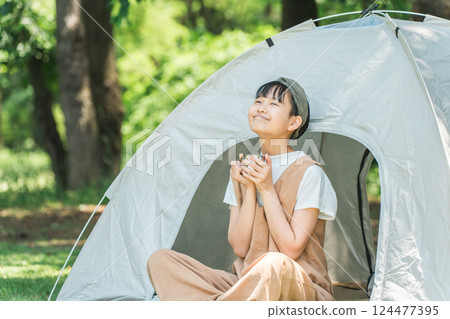 在露營地/休閒設施的帳篷前喝飲料的女孩 在露營地/休閒設施的帳篷前喝飲料的女孩 124477395