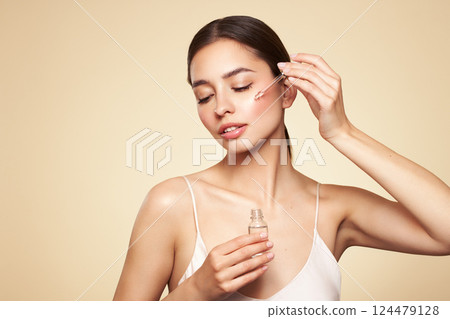 Young beautiful woman applying face serum 124479128
