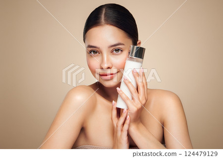 Smiling woman holds bottle with cosmetic milk 124479129