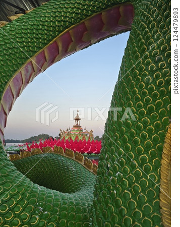 Floating shrine in pink lotus shape, seen through body of green Thai-styled dragon called naga 124479893