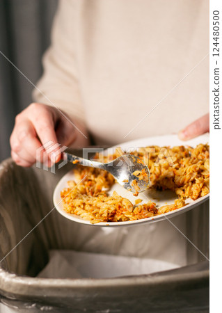 Vertical image of woman throwing away bio trash with food leftovers into garbage. Compost. Environment friendly. Stop food waste day. 124480500