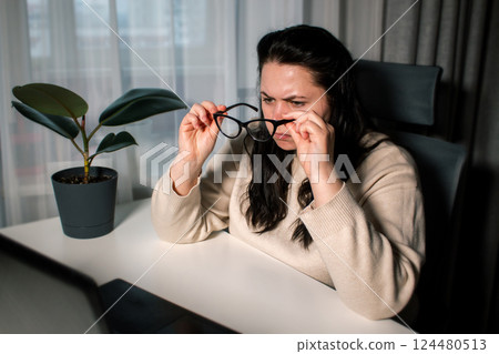 Businesswoman in home office feeling frustrated concentrating on work. Woman in eyeglasses working on computer managing working process while sitting at desk at home 124480513