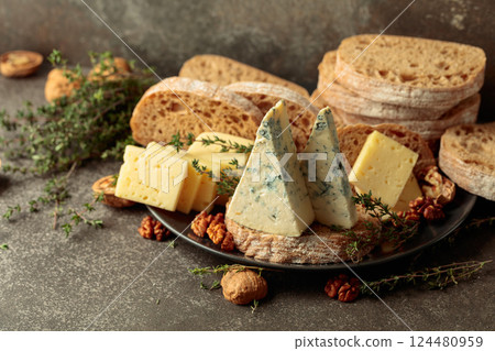 A rustic spread of cheese, bread, walnuts, and thyme on a stone kitchen table. 124480959