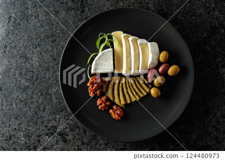 Creamy Camembert with savory olives, fragrant rosemary, and crunchy walnuts on a black plate. Creamy Camembert with savory olives, fragrant rosemary, and crunchy walnuts on a black plate. 124480973