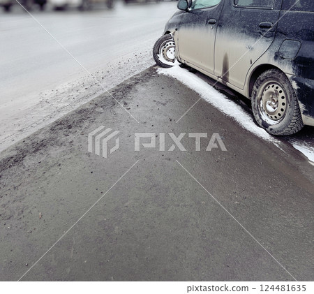 Car with damaged tire on the side of the road on a winter snowy day. The parked vehicle exhibits signs of winter driving challenges in a bustling city environment Car with damaged tire on the side of the road on a winter snowy day. The parked vehicle exhibits signs of winter driving challenges in a bustling city environment 124481635