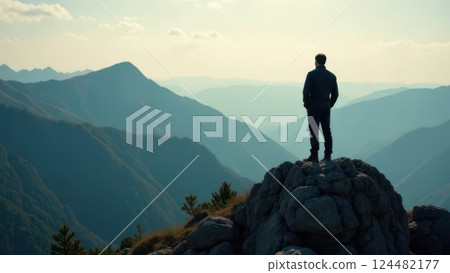 Hiker standing on top of a mountain and enjoying the sunset over the valley 124482177
