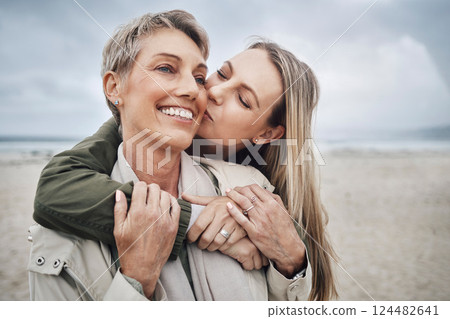 Kiss, mother and daughter at beach smile, hug and kiss with smile together in Australia. Happy face of young woman with a senior mom in the sea or ocean together with love and to relax in happiness 124482641