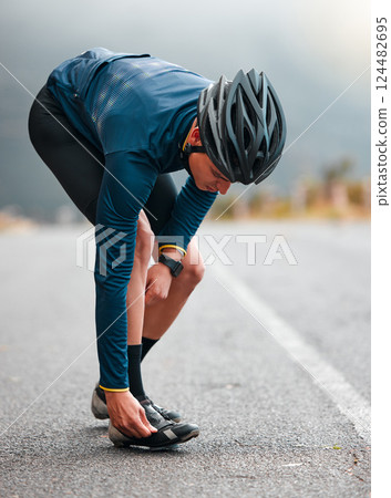 Cycling, man and shoes preparation on road for outdoor sports adventure, triathlon or workout. Fitness, training and athlete cyclist man on street with helmet getting ready for cycle exercise. 124482695