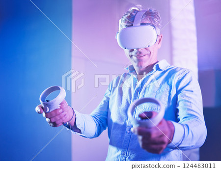 Metaverse, virtual reality headset or gaming console for mature man in neon house, home and studio. Smile, happy and vr gamer in futuristic cyber world, 3d ai software and interactive esports control Metaverse, virtual reality headset or gaming console for mature man in neon house, home and studio. Smile, happy and vr gamer in futuristic cyber world, 3d ai software and interactive esports control 124483011