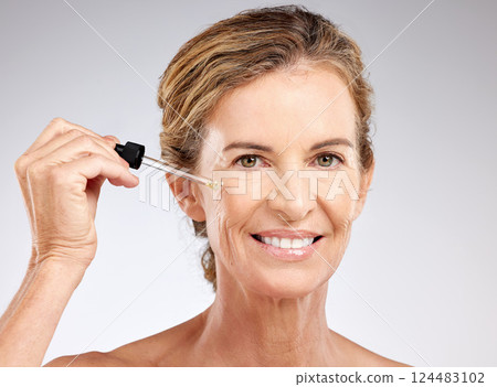 Elderly, woman and skincare with serum, cosmetic and beauty against grey, studio or background. Model, smile and skin for makeup, cosmetics and senior with happiness, anti-aging and care for health 124483102