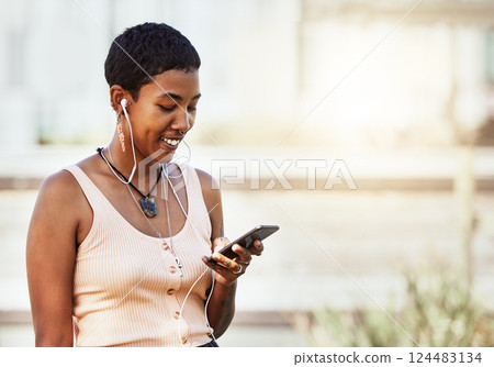 Black woman, smile and smartphone with earphones, music and communication, social media and audio streaming online. African American person, listening to podcast or radio, connection and technology. Black woman, smile and smartphone with earphones, music and communication, social media and audio streaming online. African American person, listening to podcast or radio, connection and technology. 124483134