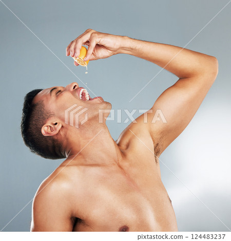 Health, man and orange fruit for vitamin c for skincare, wellness and immune booster against grey background in studio. Male model, healthy cosmetics and natural beauty for dermatology advertisement Health, man and orange fruit for vitamin c for skincare, wellness and immune booster against grey background in studio. Male model, healthy cosmetics and natural beauty for dermatology advertisement 124483237