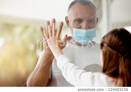 Covid, window and lockdown father with child for family hand touch with social distance protocol. Love, daughter and dad with quarantine mask protection at glass for communication with young kid. Covid, window and lockdown father with child for family hand touch with social distance protocol. Love, daughter and dad with quarantine mask protection at glass for communication with young kid. 124483239