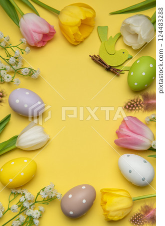 Easter eggs and tulips forming a frame on yellow background Easter eggs and tulips forming a frame on yellow background 124483288