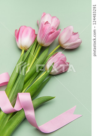 Pink tulips with ribbon on pastel green background for spring holidays 124483291