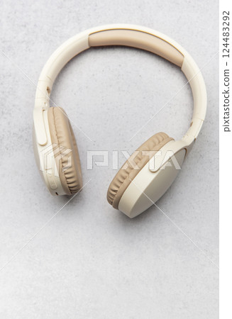 Modern wireless headphones lying on gray stone background 124483292
