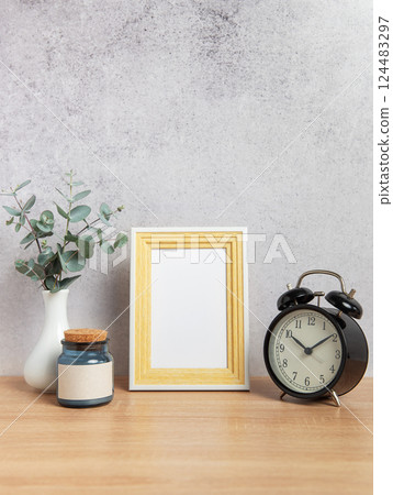 Empty photo frame, alarm clock, eucalyptus branches and jar on wooden table 124483297