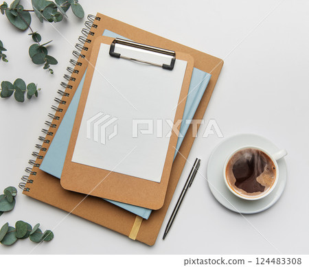 Clipboard with blank paper, notebooks and coffee cup on white table 124483308