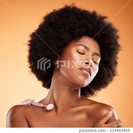 Beauty, skincare and facial on black woman and jade roller for massage, wellness and spa with natural cosmetics. Salon, relax and health with girl for luxury, product and natural in orange background 124483404