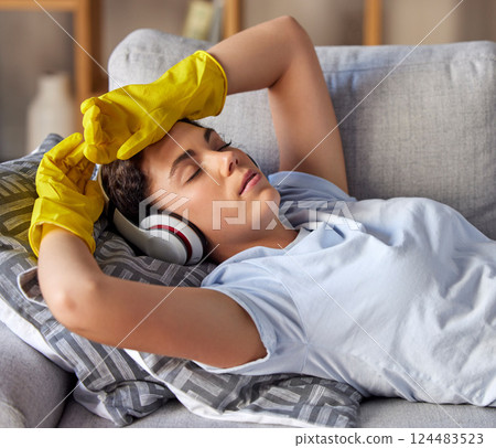 Sofa, headphones and woman cleaner sleep, relax and listening to music after cleaning work in home living room. Calm, tired and fatigue girl on a couch in her lounge with audio streaming service app 124483523