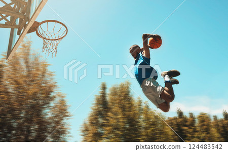 Basketball, sports and dunk with a man athlete jumping or flying through the air to score while playing on an outdoor court against the sky. Sport, fitness and exercise with a male basketball player Basketball, sports and dunk with a man athlete jumping or flying through the air to score while playing on an outdoor court against the sky. Sport, fitness and exercise with a male basketball player 124483542