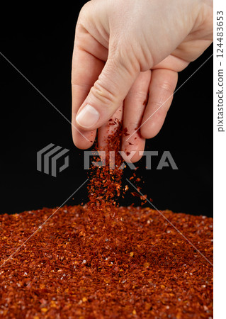 Hand pouring dried ground red chili peppers, natural seasoning, close-up 124483653
