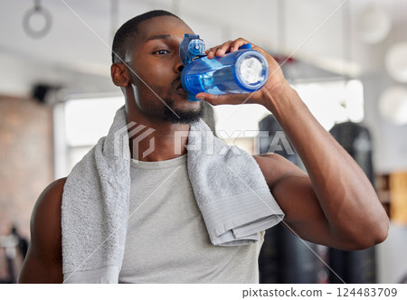 Water, drink and fitness with a sports man in a gym for exercise while taking a break to hydrate. Workout, training and drinking with a male athlete taking a sip from a bottle after his routine 124483709