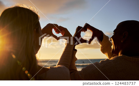 Heart hands, love and couple on beach for summer, outdoor health and wellness with sunset sky and silhouette. Happy woman or people with care sign for ocean, sea holiday or vacation together 124483737
