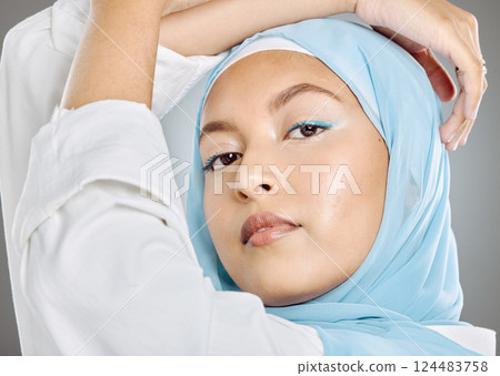 Muslim, woman and face in beauty makeup or cosmetics with hijab against a grey studio background. Portrait of beautiful female model wearing blue scarf posing for fashion, style or islamic culture 124483758