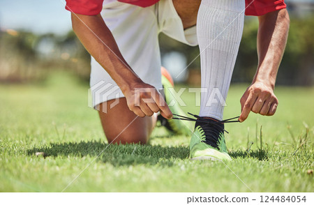 Hands, shoes and soccer player at a soccer field, tie lace and prepare for training, sports and fitness game. Football, hand and football player getting ready for workout, exercise and sport practice 124484054