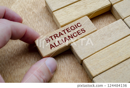 Hand pulling Strategic Alliances text text on wooden block. Business strategy concept 124484136