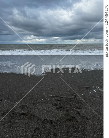 Black sand beach with ocean waves and moody clouds 124484170