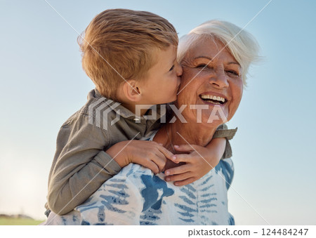 Kiss, child and grandmother in a park with love, care and freedom for happiness in retirement. Senior, smile and portrait of a woman with hug from a kid and kissing in nature or park with piggyback 124484247
