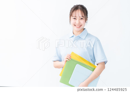一位年輕的護理員婦女拿著文件,白色背景 一位年輕的護理員婦女拿著文件,白色背景 124485925