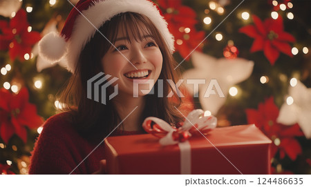 Smiling woman holding a Christmas gift Smiling woman holding a Christmas gift 124486635
