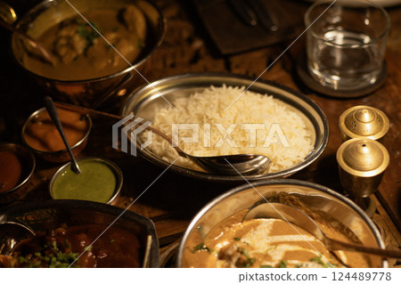 table covered with Indian dishes, rice in a plate close-up 124489778
