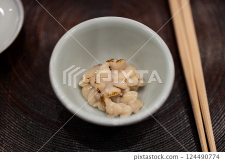 Japanese appetizer featuring natto in a small ceramic bowl placed on a wooden tray with chopsticks 124490774