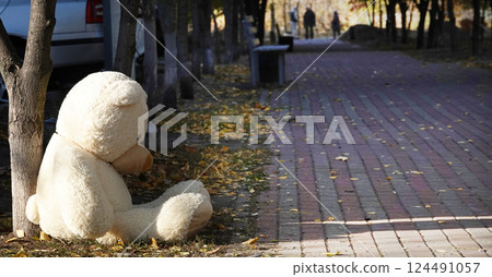 Kyiv, Ukraine March 11, 2022: A large teddy bear thrown into the garbage sitting near a dumpster 124491057