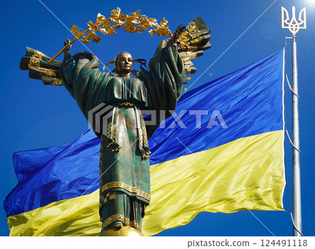 Kyiv, Ukraine July 20, 2020: A monument dedicated to the independence of Ukraine against the background of the largest Flag of Ukraine 124491118