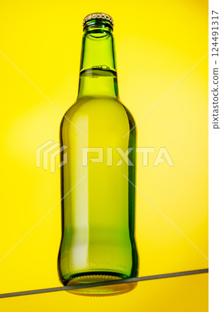 A cold beer bottle standing on a glass table 124491317