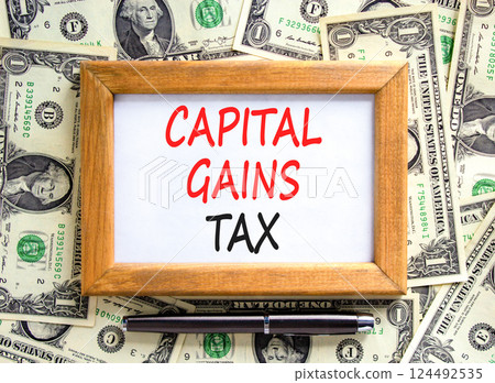 Capital gains tax symbol. Concept words Capital gains tax on beautiful wooden picture frame. Black pen. Beautiful background from dollar bills. Business and capital gains tax concept. Copy space. Capital gains tax symbol. Concept words Capital gains tax on beautiful wooden picture frame. Black pen. Beautiful background from dollar bills. Business and capital gains tax concept. Copy space. 124492535