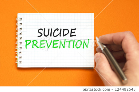 Suicide prevention symbol. Concept words Suicide prevention on beautiful white note. Psychologist hand. Beautiful orange table orange background. Psychological suicide prevention concept. Copy space. 124492543
