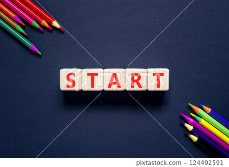Start symbol. Concept word Start on beautiful wooden blocks. Beautiful black table black background. Beautiful colored pencils. Business lifestyle start concept. Copy space. Start symbol. Concept word Start on beautiful wooden blocks. Beautiful black table black background. Beautiful colored pencils. Business lifestyle start concept. Copy space. 124492591