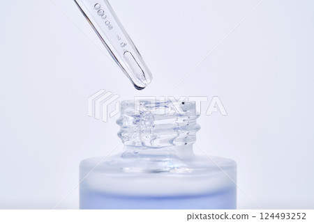 The blue serum drips from the dropper into the bottle. 124493252