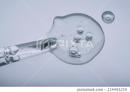 Pipette with serum on a blue background. Product texture. Pipette with serum on a blue background. Product texture. 124493259